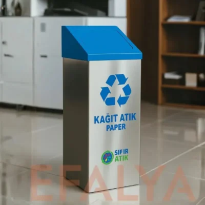 Modern bir ofis ortamında, parlak zemin üzerinde konumlandırılmış; mavi yaylı kapaklı, üzerinde "KAĞIT ATIK PAPER" ve "SIFIR ATIK" logosu bulunan 304 kalite paslanmaz çelik geri dönüşüm kutusu.